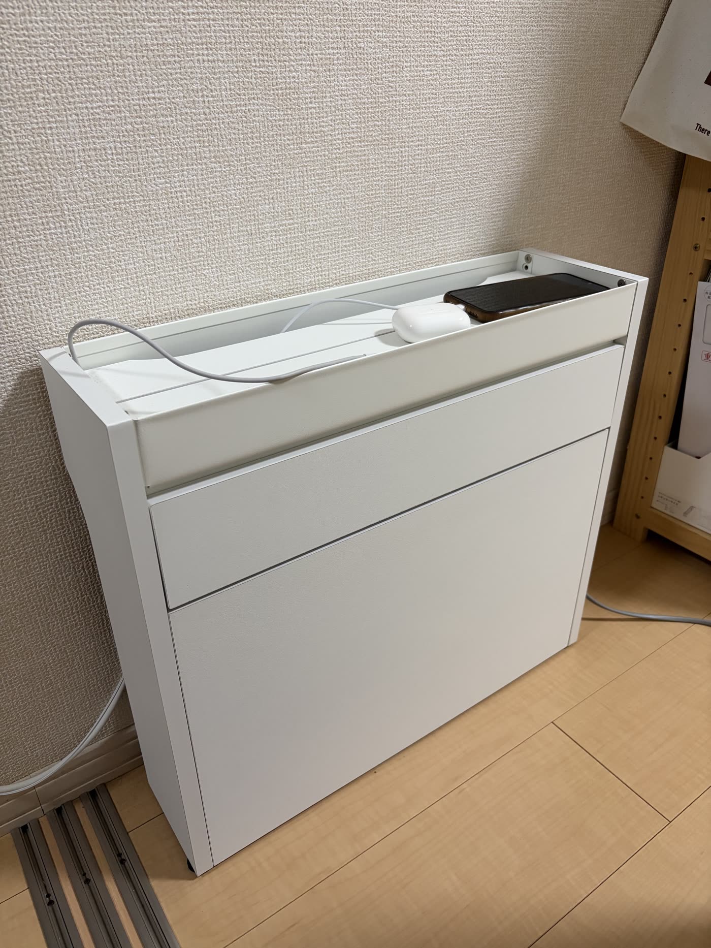 ルーター・電源タップ収納ボックスの外観。天板の上でスマホとAirPodsを充電している